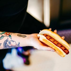 Tattooed Arm Holding a Hotdog at Harrell's Hot Dogs & Cold Cones