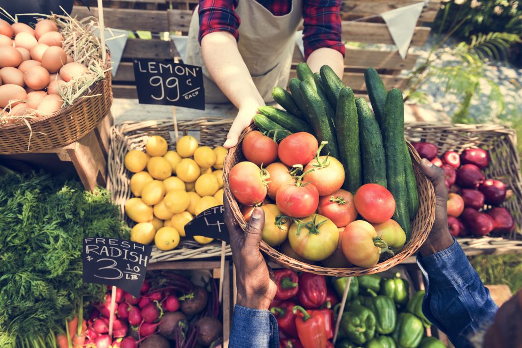 Vandor handing a basket of fresh veggies to a customer