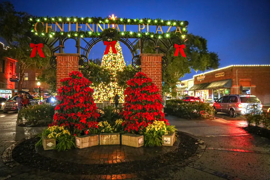 Centennial Plaza decorated with poinsettias and a Christmas tree at night