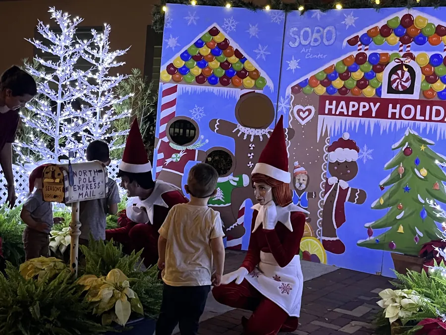 Families at a gingerbread-themed holiday photo station