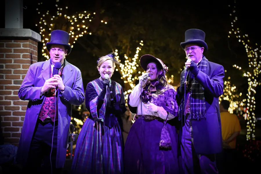 Carolers in Victorian costume singing on the plaza