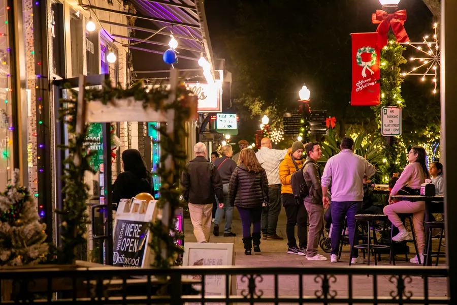 Shoppers along a decorated downtown sidewalk at night